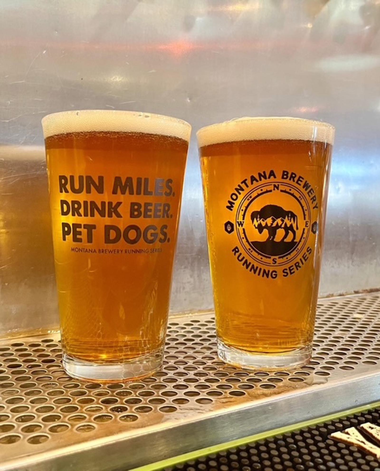 Two pints of beer on a bar counter. The left glass reads "Run miles. Drink beer. Pet dogs." and the right glass shows a logo for the Montana Brewery Running Series with an image of a bear.
