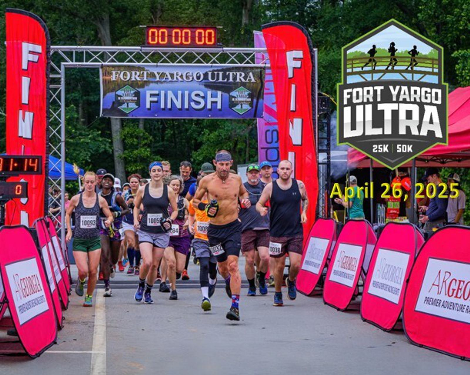 Runners at the start of the Fort Yargo Ultra marathon, with a banner overhead and red signs marking the course. The digital clock shows 00:00:00. Date and distances (25K and 50K) are displayed on the right.