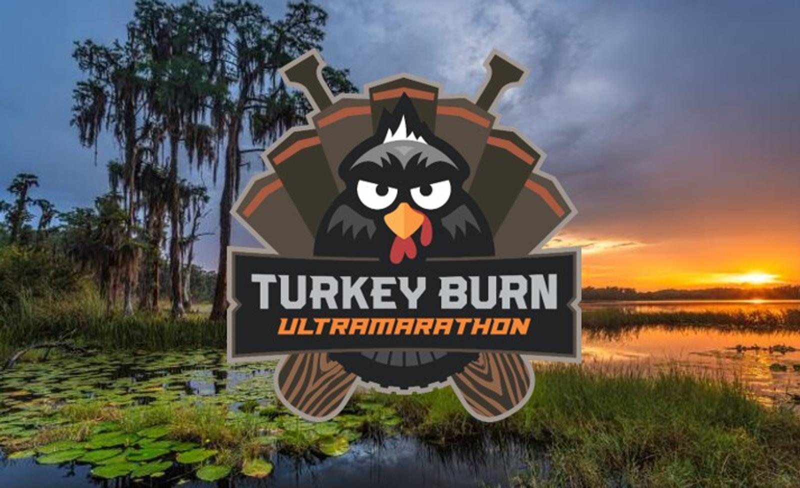 A logo featuring an angry cartoon turkey and the text "Turkey Burn Ultramarathon" is centered over a scenic wetland landscape at sunset, with tall trees, lily pads, and a colorful sky.