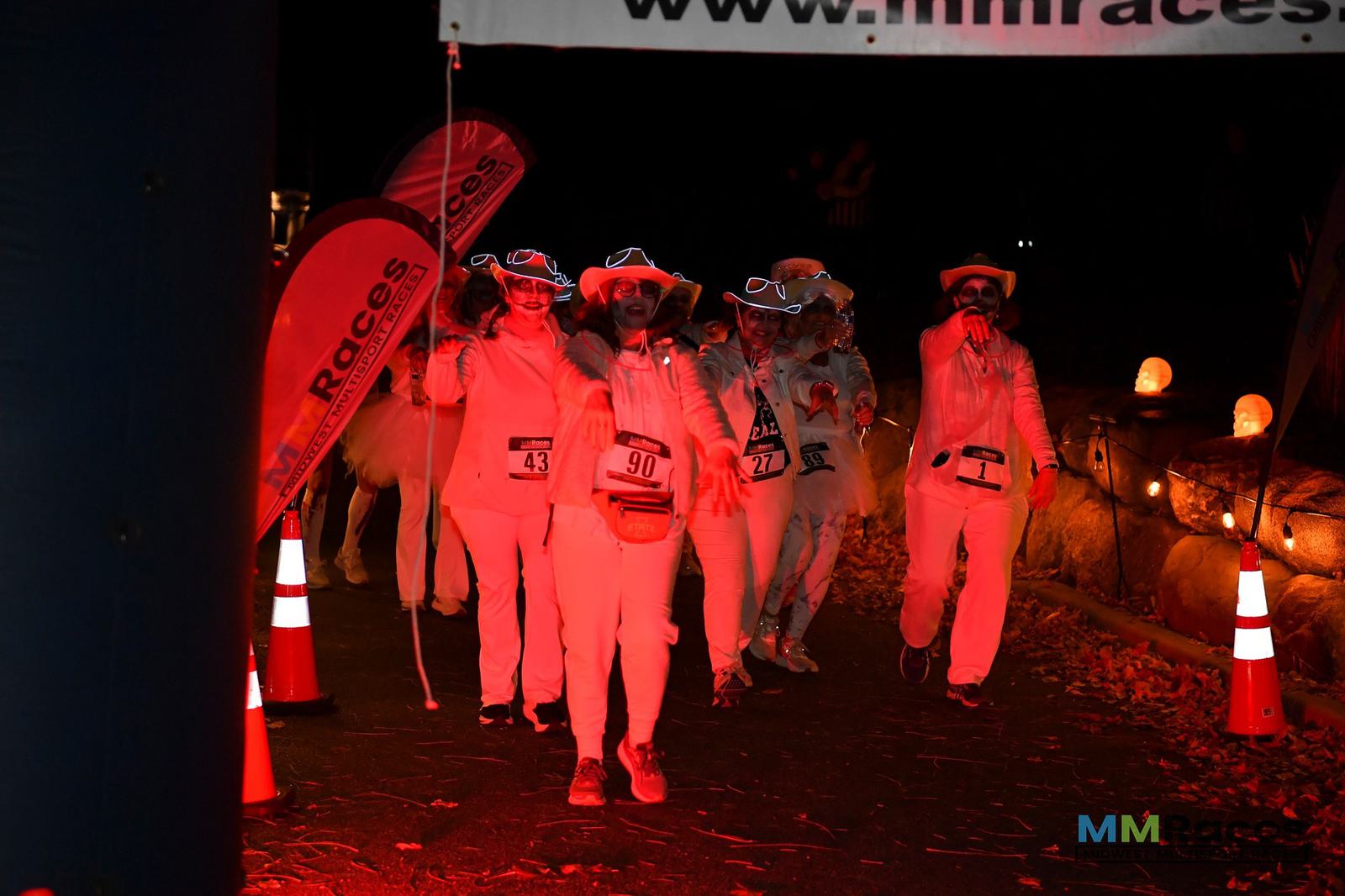 A group of people in white outfits walking on a road.