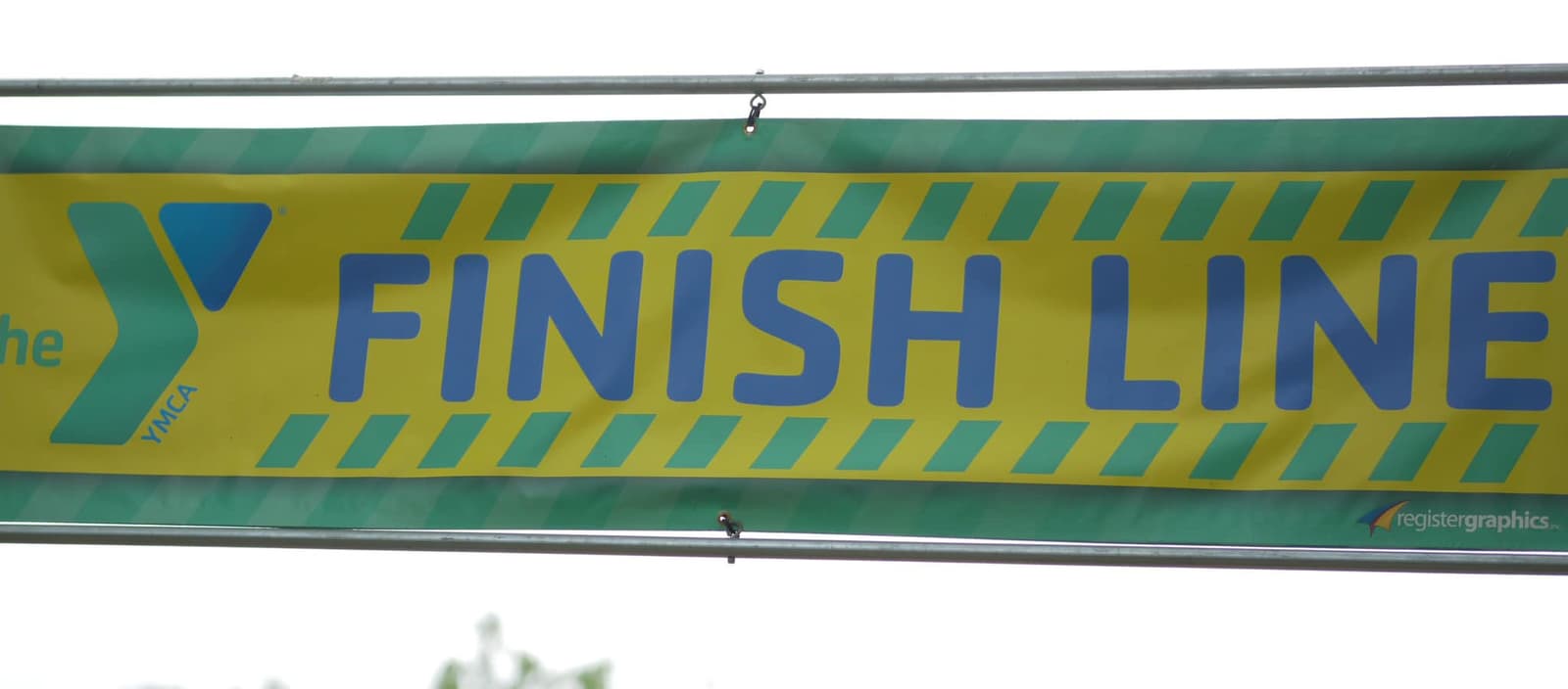 A yellow and green banner reads "FINISH LINE" with the YMCA logo on the left side, hanging outdoors.