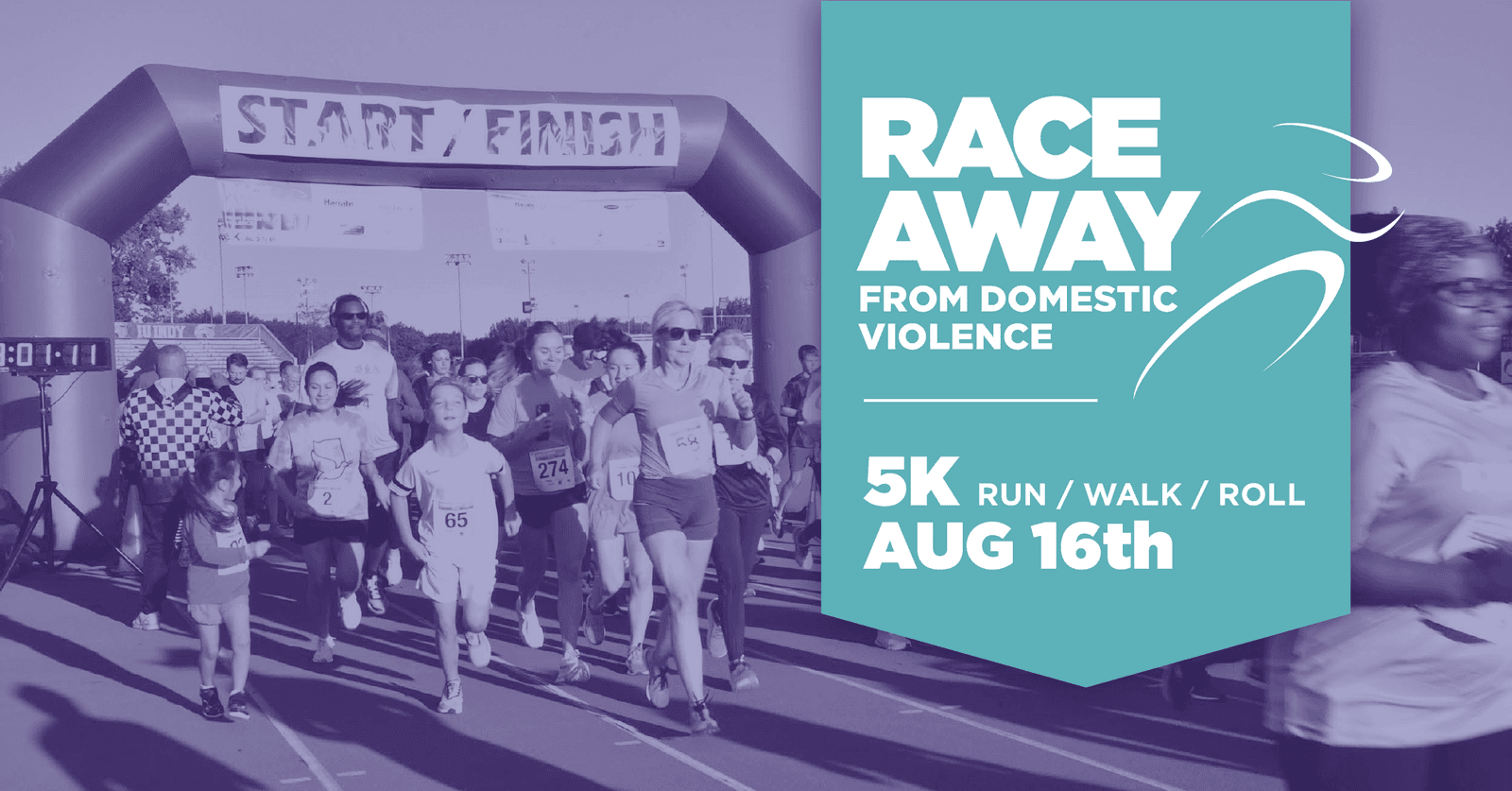 A group of people participate in a 5K race under a βStart/Finishβ arch. A large sign reads: βRace Away from Domestic Violence. 5K Run/Walk/Roll. Aug 16th.β.