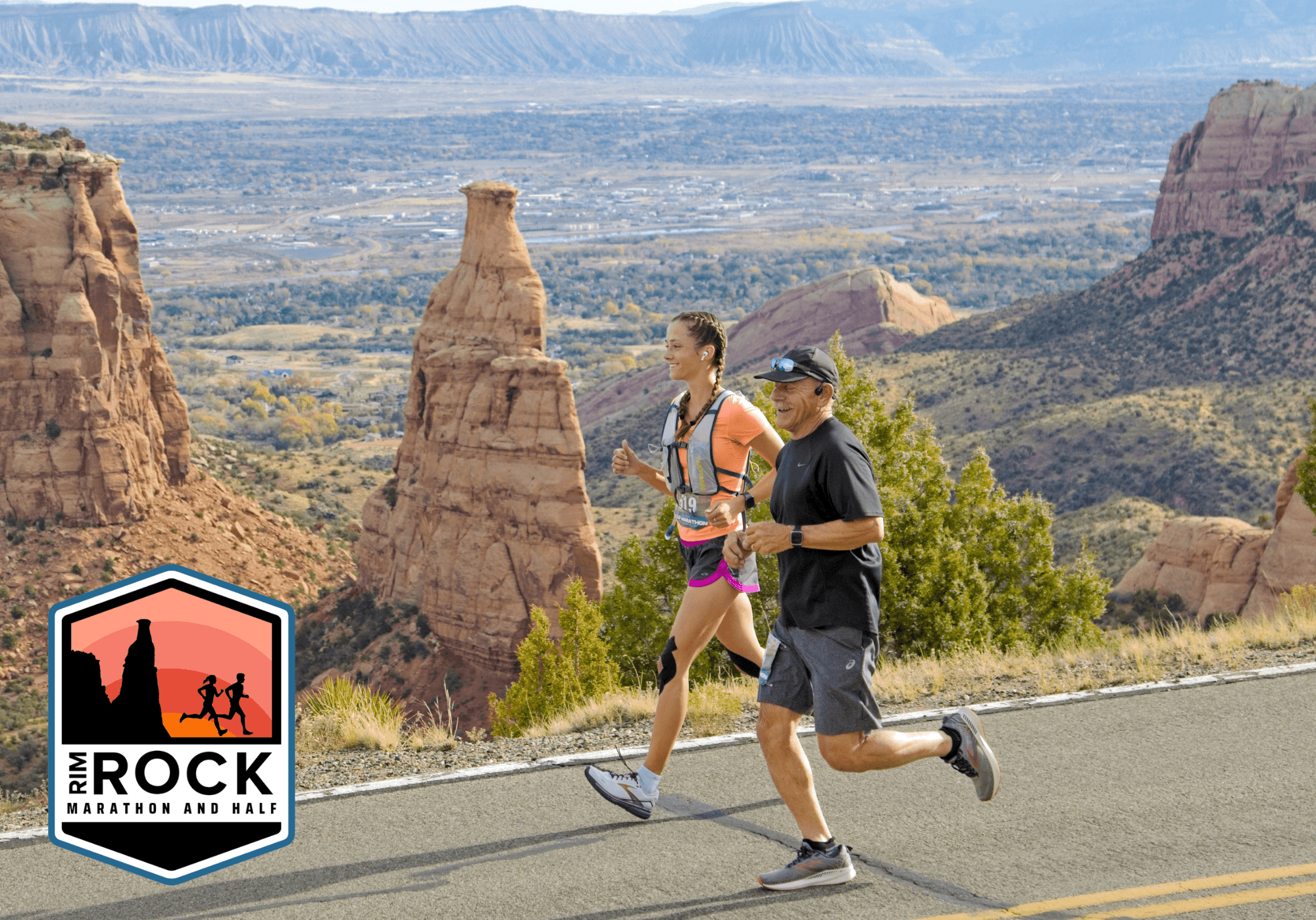 Two runners jog along a road beside dramatic red rock formations and canyons under a bright sky. A “Rim Rock Marathon and Half” logo appears in the lower left corner.