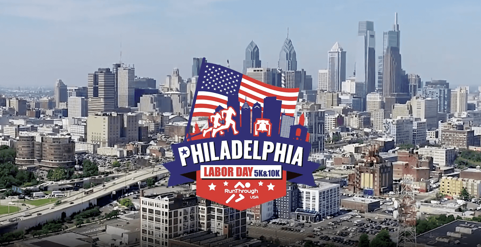 A logo for the Philadelphia Labor Day 5k/10k race is overlaid on a cityscape of Philadelphia, featuring skyscrapers and a clear sky. The logo includes an American flag, runners, and city skyline graphics.