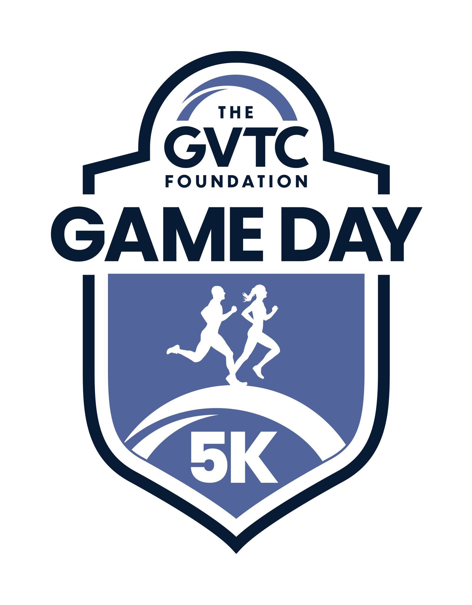 Shield-shaped logo for "The GVTC Foundation Game Day 5K," featuring silhouettes of a man and a woman running on a curved path inside the shield. The design uses blue and white colors.