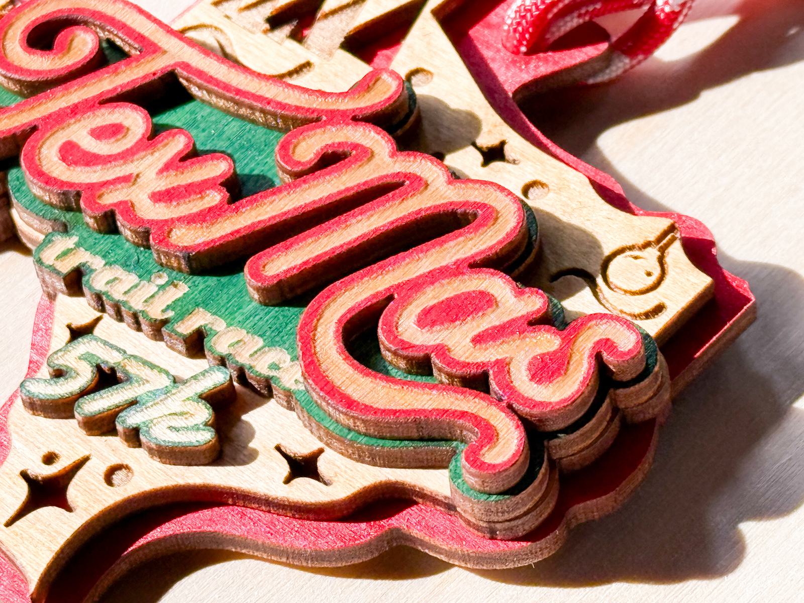 A wooden ornament shaped like Texas, painted in red, green, and natural tones, reads "TexMas trail race 5K," with festive decorative stars and a red ribbon for hanging.